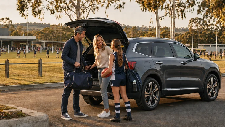 Australian family beside a Kia Sorento at a regional community AFL game